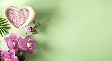 A cup of sea salt for taking spa treatments with orchid flowers on a green background.