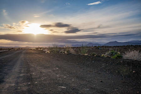 Sunrise with clouds over a dirt road in the Karoo, Prins Albert, South Africa