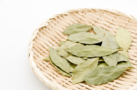Dried bay leaves on bamboo sieve on white background.の写真素材