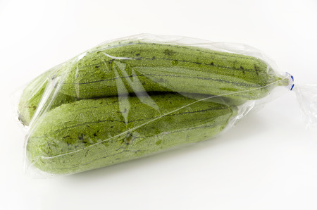 fresh green sponge gourd or luffa on black stone plate.の写真素材