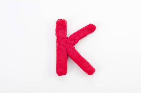 Red plasticine letter K uppercase of English alphabet isolated on white backgroundの写真素材