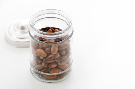 Glass jar with acorns on white backgroundの写真素材