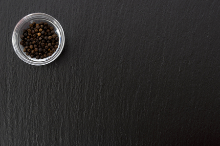 Black pepper in stacking bowl on black stone plateの写真素材