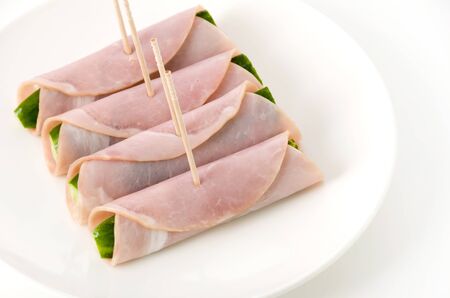 fresh Cucumber wrapped in loin ham on a dish on white backgroundの写真素材