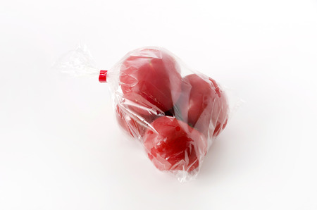 Ripe red Tomatoes in Plastic bag on white backgroundの写真素材