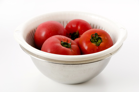 Ripe red Tomatoes in colander with Stainless steel bowl on white backgroundの写真素材