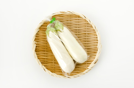 White eggplant in Plastic bag on bamboo colander  on white backgroundの写真素材