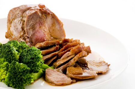 Roasted pork with sauce and broccoli on white plateの写真素材