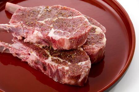 Raw lamb chops on red tray on White background