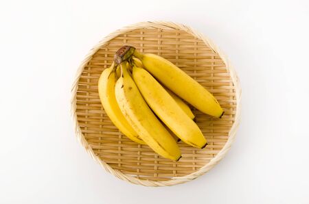 Bunch of bananas on bamboo colander on white backgroundの写真素材