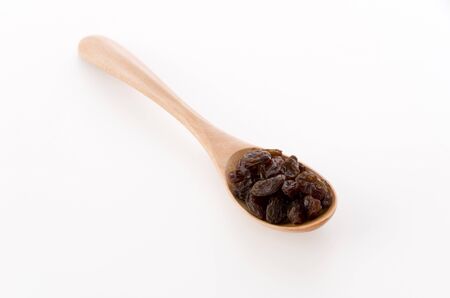 Raisins in a wooden spoon on whiteの写真素材
