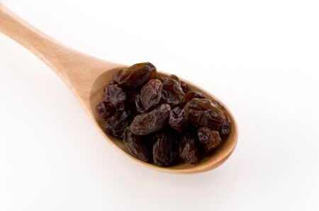 Raisins in a wooden spoon on whiteの写真素材