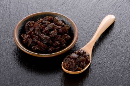 Raisins in small dish on black stoneの写真素材