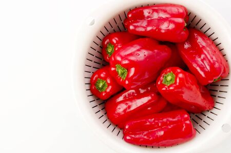 fresh Red bell pepper in plastic Colander with Stainless steel bowl on on white backgroundの写真素材
