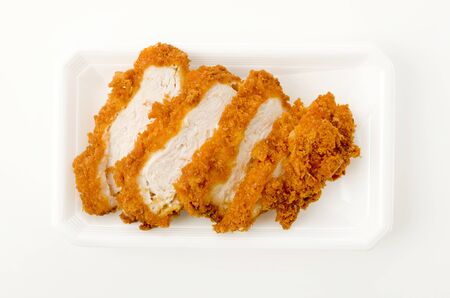 Sliced breaded chicken breast on a tray on white backgroundの写真素材