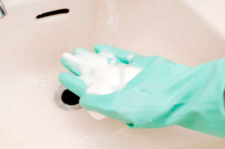 hand in a rubber glove washes the wash basin with details. soap foam on the handsの写真素材