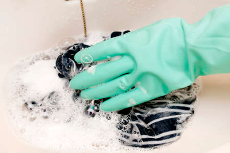 hand in a rubber glove washes clothing