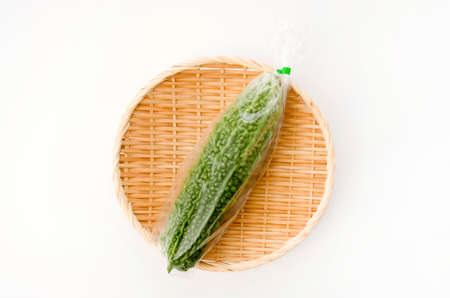 Goya, Bitter melon in plastic bag bamboo sieve on white backgroundの写真素材
