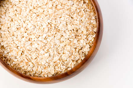 Oatmeal in a wooden round bowl on white backgroundの写真素材