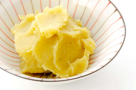 Mashed cooked sweet potatoes in a bowl on white background