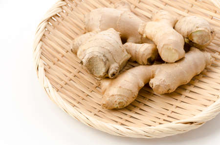 fresh ginger on a bamboo sieve on white backgroundの写真素材