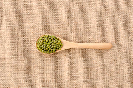 mung beans in wooden spoon over burlap backgroundの写真素材