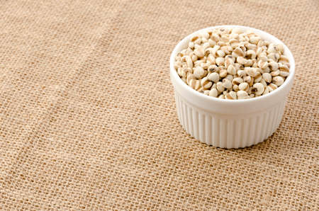 Job's tears( Adlay millet) in ceramic cocotte on burlap background
