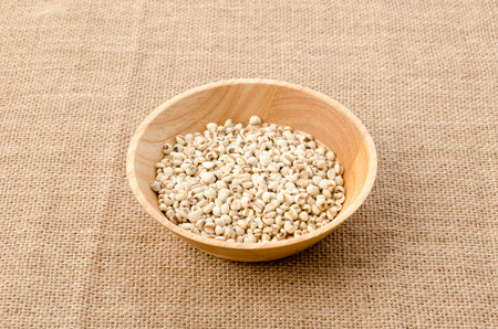 Job's tears( Adlay millet) in wooden bowl on burlap backgroundの写真素材