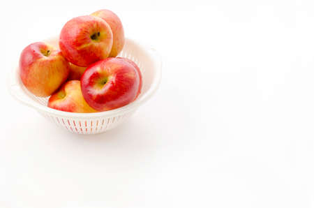 Jazz apples in white plastic colander on white backgroundの写真素材