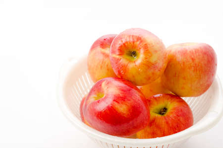 Jazz apples in white plastic colander on white backgroundの写真素材