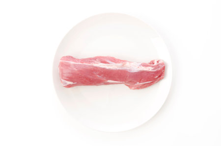 Raw pork fillet on white plate on white background