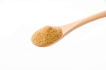 Powdered brown sugar on wooden spoon on white backgroundの写真素材