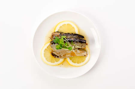 Sardines with slice lemon on a white plate