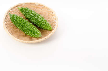 fresh Goya, bitter gourd on a bamboo sieve on a white backgroundの写真素材