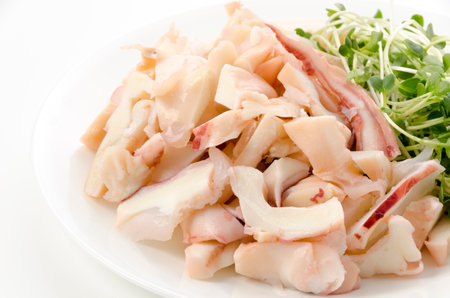 Boiled squid legs with Radish sprouts on a plate on white backgroundの写真素材