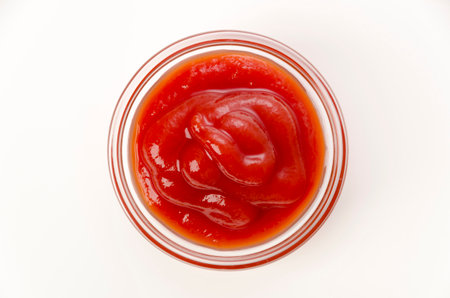 tomato ketchup in a small glass bowl on a white backgroundの写真素材