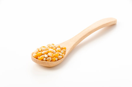 popcorn seeds in wooden spoon on white background
