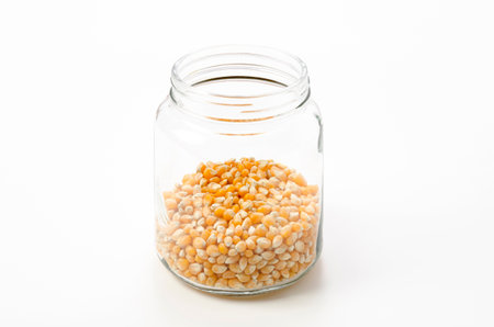 popcorn seeds in transparent glass jar on white backgroundの写真素材