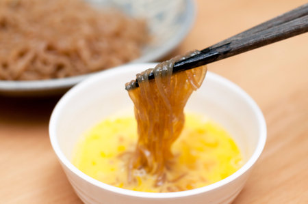 Sweet and spicy boiled Konjac noodles is dipped into a raw egg.の写真素材