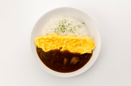 Japanese curry rice topped with Omelet in a white dish on white background.の写真素材