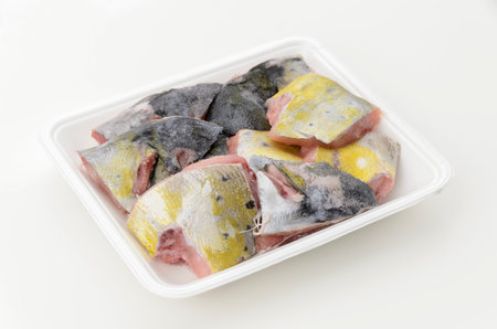 Fish scraps of mahi-mahi in a foam food tray on a white background.