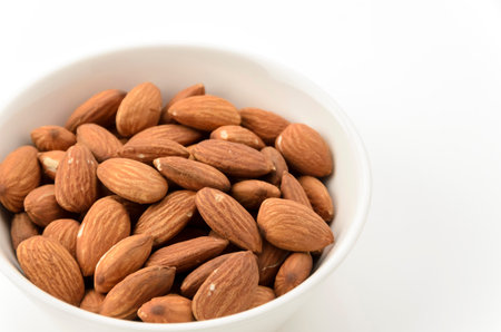 unglazed almonds in a white bowl on a white backgroundの写真素材