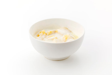 white ceramic bowl of yogurt with pineapple pieces isolated on white backgroundの写真素材