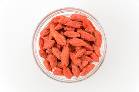 Dried goji berries in a glass bowl on white background