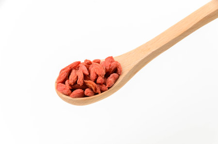 Dried goji berries on a wooden spoon on white backgroundの写真素材