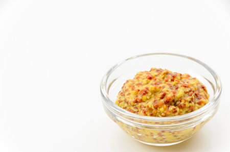 whole grain mustard in small glass bowl on white backgroundの写真素材