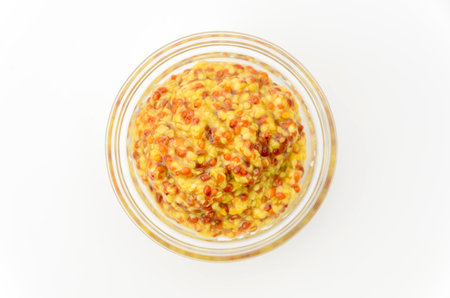 whole grain mustard in small glass bowl on white backgroundの写真素材