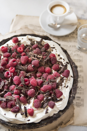 Chocolate tart with raspberries on a vintage background and a cup of fragrant espresso macchiato.の写真素材