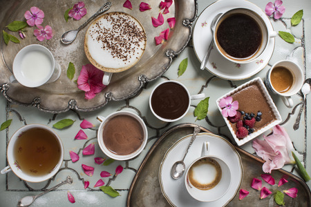 Coffee latte, espresso, tea, hot chocolate and dessert on the background of an antique table and silver trays and old spoonsの写真素材