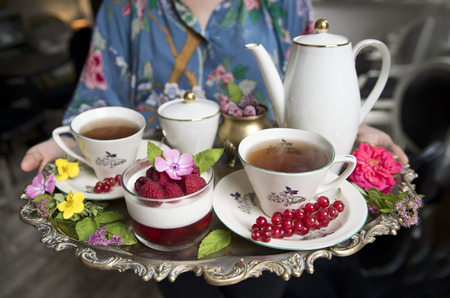 Magnificent fresh hot tea in ancient cups on a silver vintage tray and a raspberries dessert, an antique teapotの写真素材